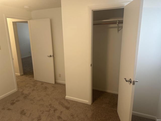 unfurnished bedroom with a closet, baseboards, and carpet flooring