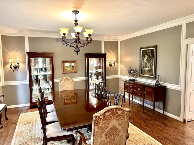 dining space with a chandelier, dark wood-type flooring, and crown molding