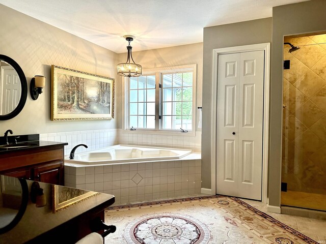 bathroom with tile patterned floors, vanity, independent shower and bath, and an inviting chandelier