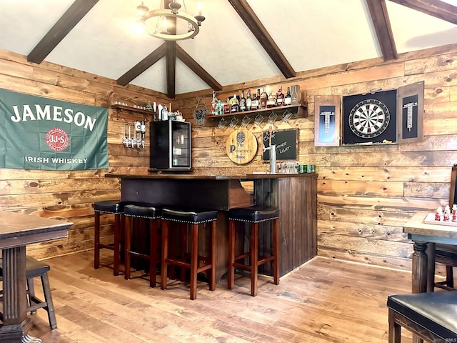 bar featuring a chandelier, wood walls, lofted ceiling with beams, and hardwood / wood-style flooring