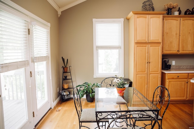 dining area with lofted ceiling, light wood finished floors, baseboards, and ornamental molding