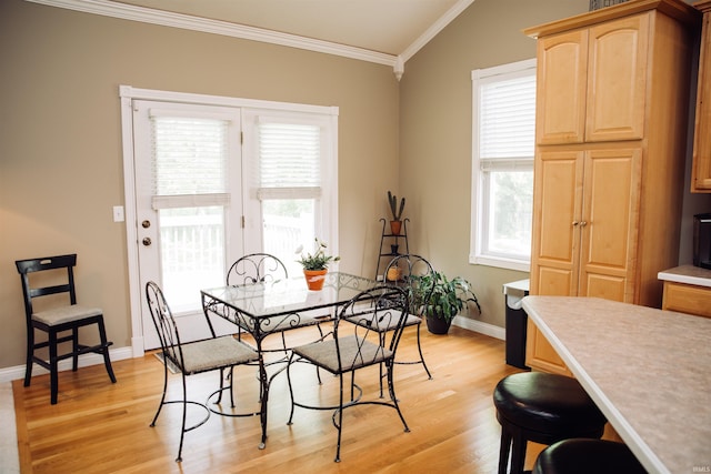 dining space with light wood-style floors, a healthy amount of sunlight, and crown molding