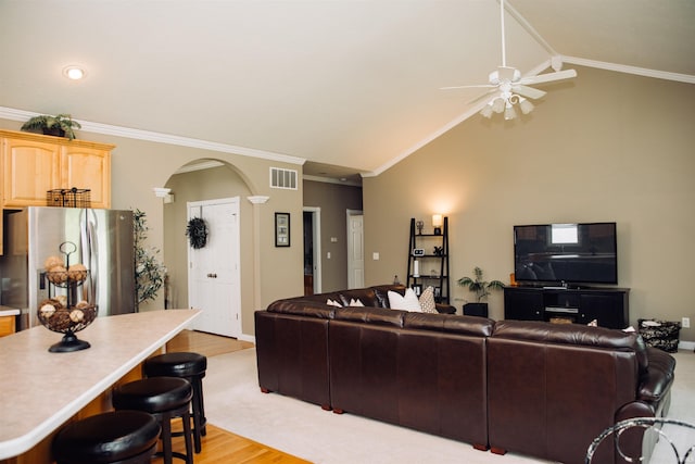 living room with arched walkways, visible vents, light wood-style floors, vaulted ceiling, and ornamental molding