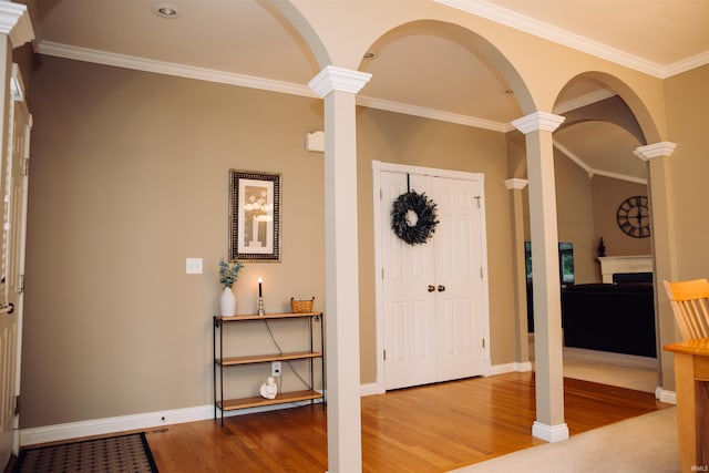 entryway with baseboards, crown molding, decorative columns, and wood finished floors