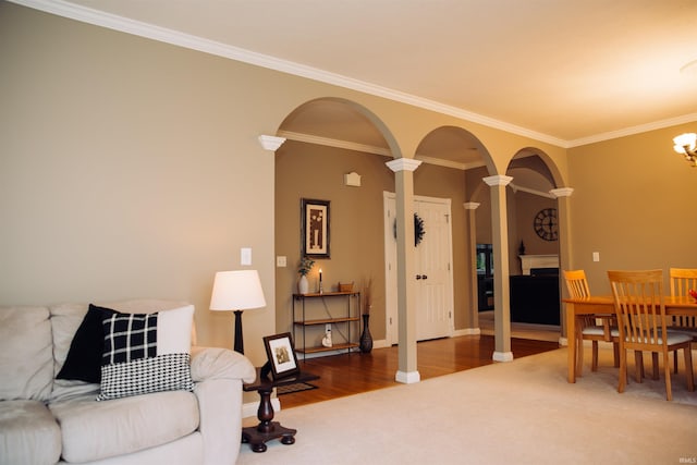 living room featuring decorative columns, arched walkways, ornamental molding, wood finished floors, and carpet flooring