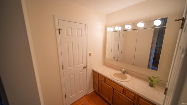 bathroom featuring vanity, wood-type flooring, and a textured ceiling