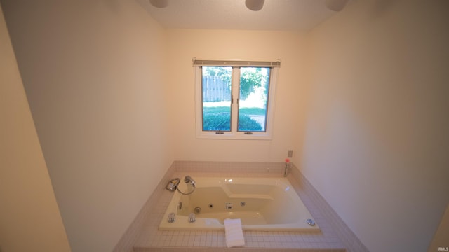 bathroom featuring a textured ceiling and tiled bath