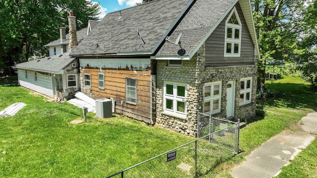 rear view of property featuring a lawn and central AC