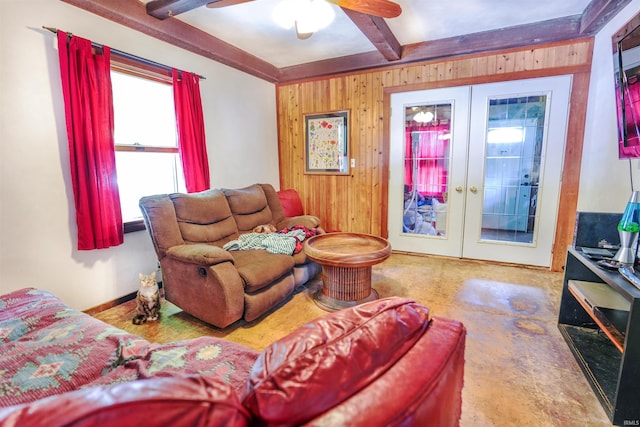 living room with beamed ceiling, french doors, ceiling fan, and wood walls