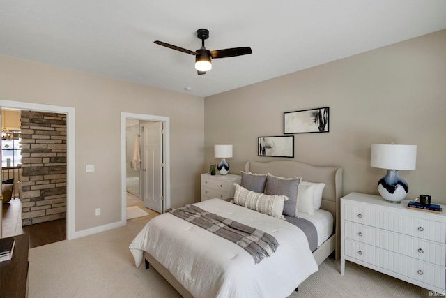 bedroom featuring a ceiling fan, baseboards, ensuite bathroom, and light carpet