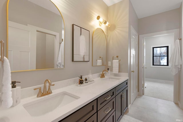 full bath with a sink, baseboards, double vanity, and tile patterned flooring