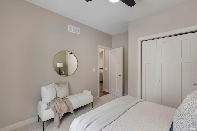 bedroom featuring visible vents, a closet, baseboards, light colored carpet, and ceiling fan