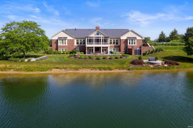 view of yard featuring a sunroom, a patio area, and a water view