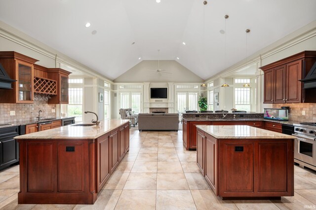 kitchen with decorative backsplash, stove, dark stone counters, sink, and pendant lighting