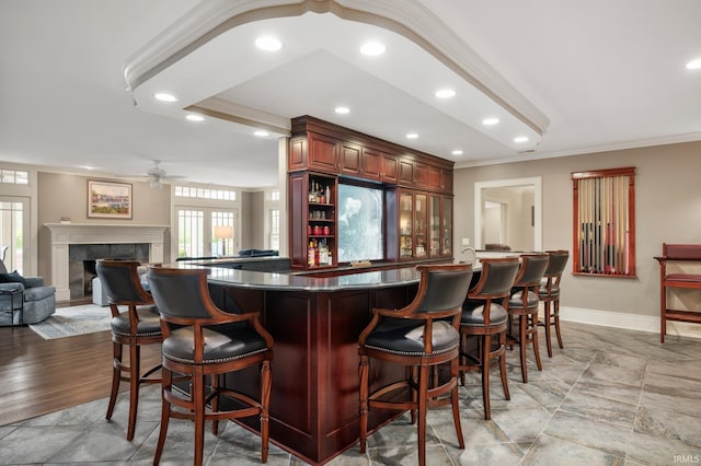 bar with ceiling fan, crown molding, and a fireplace