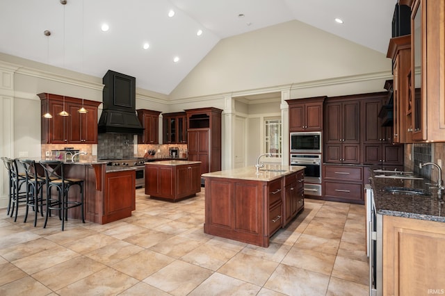 kitchen with custom range hood, stainless steel appliances, sink, a center island with sink, and high vaulted ceiling