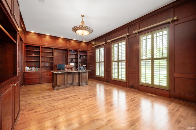 office featuring built in shelves, light wood-type flooring, and wood walls