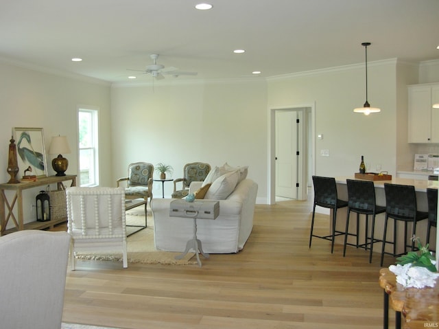 living room featuring crown molding, ceiling fan, and light hardwood / wood-style floors