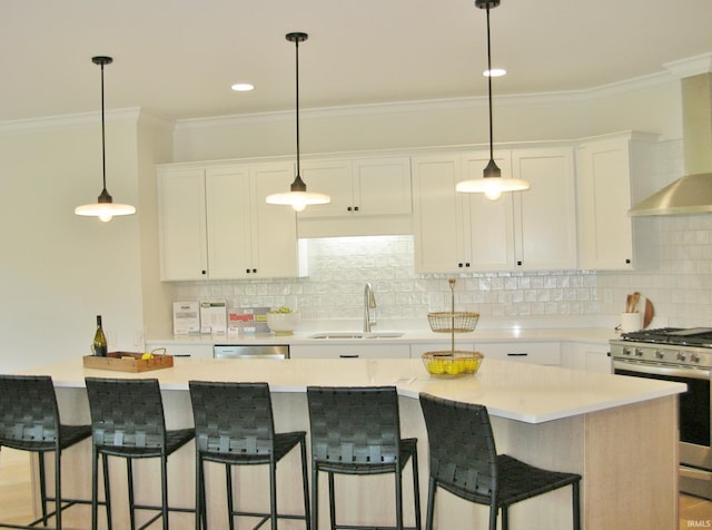 kitchen with a center island, wall chimney exhaust hood, sink, stainless steel appliances, and white cabinets