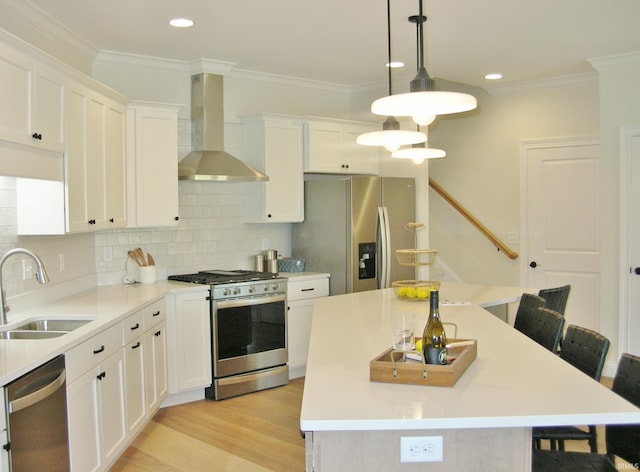 kitchen featuring sink, a center island, hanging light fixtures, stainless steel appliances, and wall chimney range hood