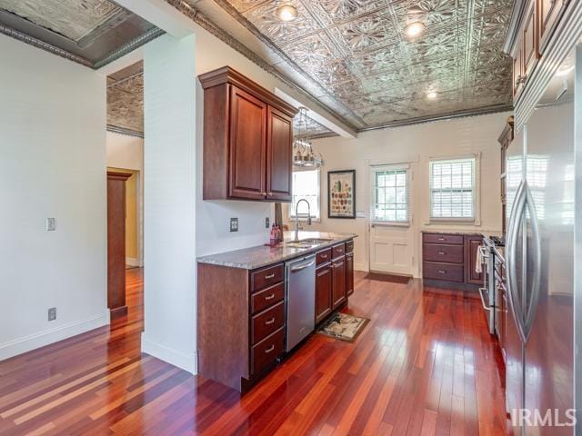 kitchen with dark hardwood / wood-style floors, light stone countertops, stainless steel appliances, and sink