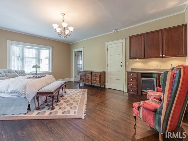 bedroom with dark hardwood / wood-style floors, crown molding, and a chandelier