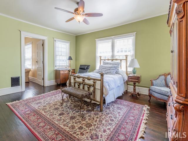 bedroom with dark hardwood / wood-style floors, ceiling fan, and ornamental molding