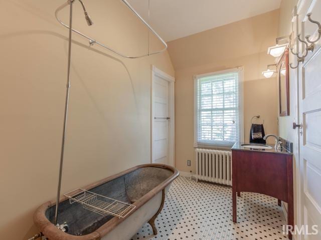 bathroom with sink, vaulted ceiling, and radiator