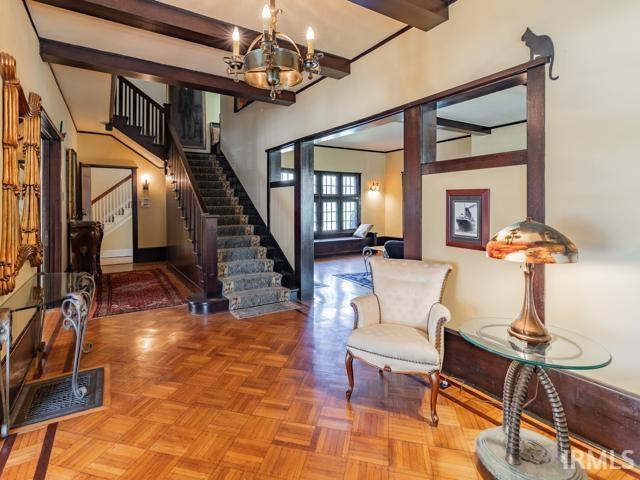 entryway featuring beam ceiling, an inviting chandelier, and parquet flooring