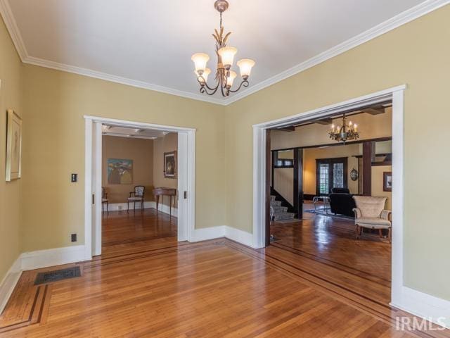 unfurnished dining area with a notable chandelier, ornamental molding, and hardwood / wood-style flooring