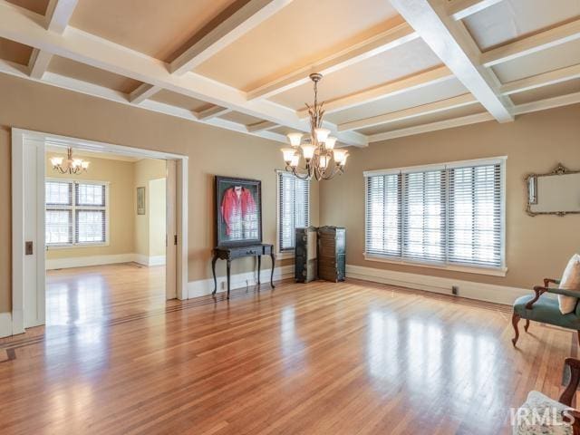 unfurnished room with a notable chandelier, beamed ceiling, hardwood / wood-style floors, and coffered ceiling