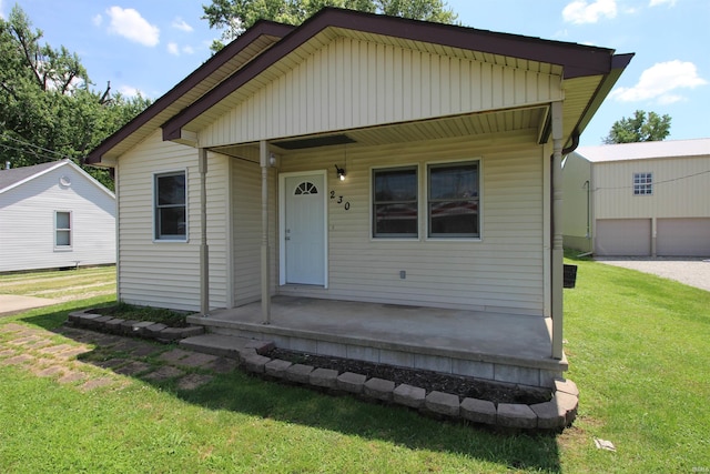 view of front of home with an outbuilding, a garage, a porch, and a front yard