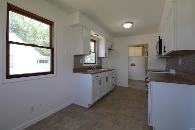 kitchen featuring tasteful backsplash, white cabinetry, sink, and a healthy amount of sunlight