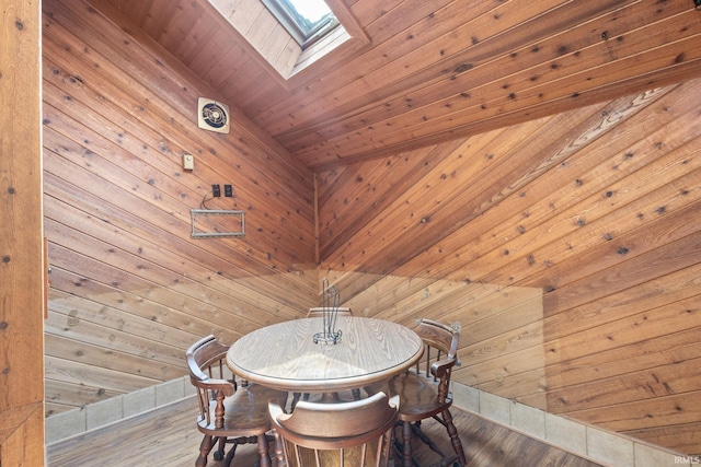 unfurnished dining area featuring a skylight, wood walls, and hardwood / wood-style floors