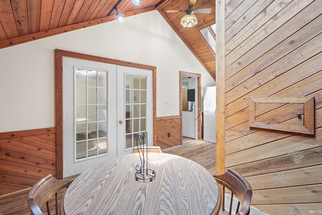 interior space with ceiling fan, french doors, wooden ceiling, wood walls, and lofted ceiling