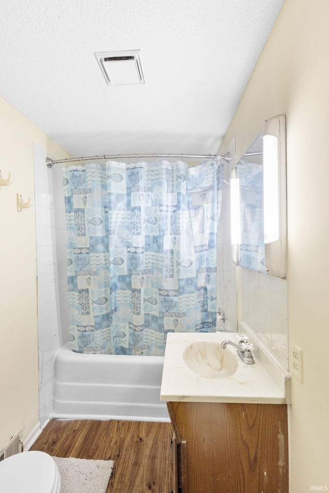 full bathroom featuring vanity, shower / bath combination with curtain, hardwood / wood-style flooring, toilet, and a textured ceiling