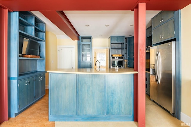 kitchen with blue cabinets, sink, kitchen peninsula, and appliances with stainless steel finishes