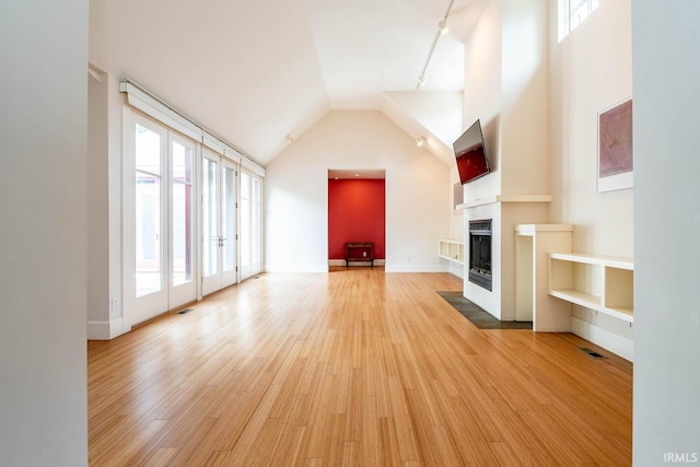 unfurnished living room featuring plenty of natural light, hardwood / wood-style floors, and rail lighting