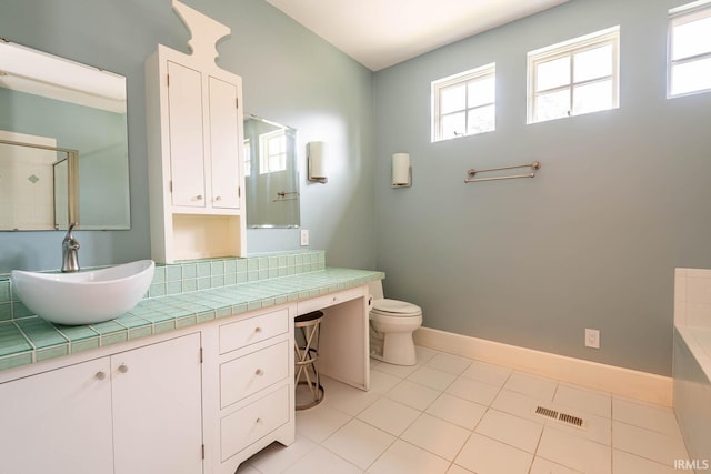 bathroom with tile floors, vanity, toilet, and a bathtub