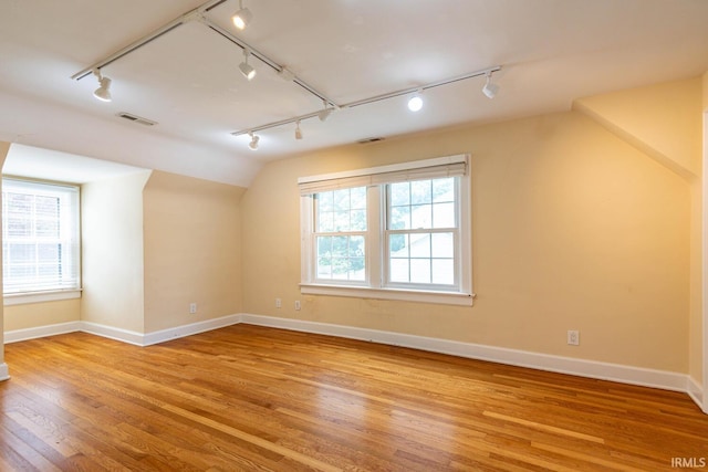 interior space featuring track lighting, light hardwood / wood-style flooring, and vaulted ceiling