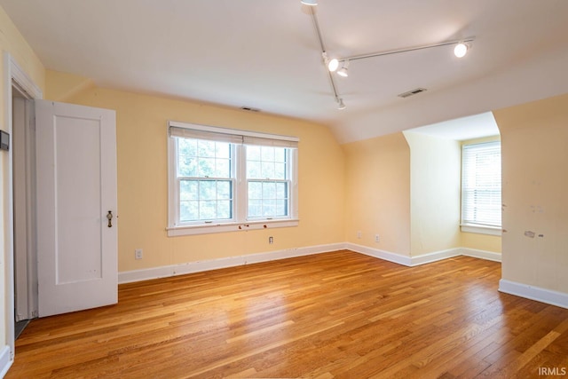 spare room featuring a wealth of natural light, track lighting, and light hardwood / wood-style floors