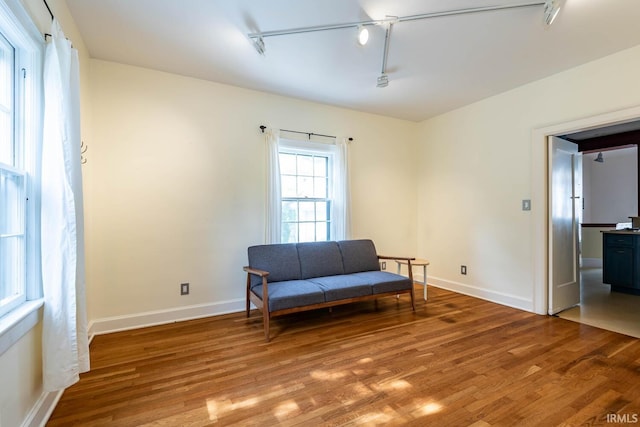 sitting room with rail lighting and wood-type flooring