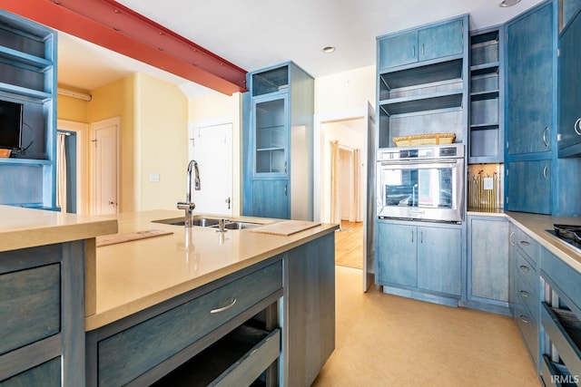 kitchen featuring light hardwood / wood-style floors, sink, blue cabinetry, and oven