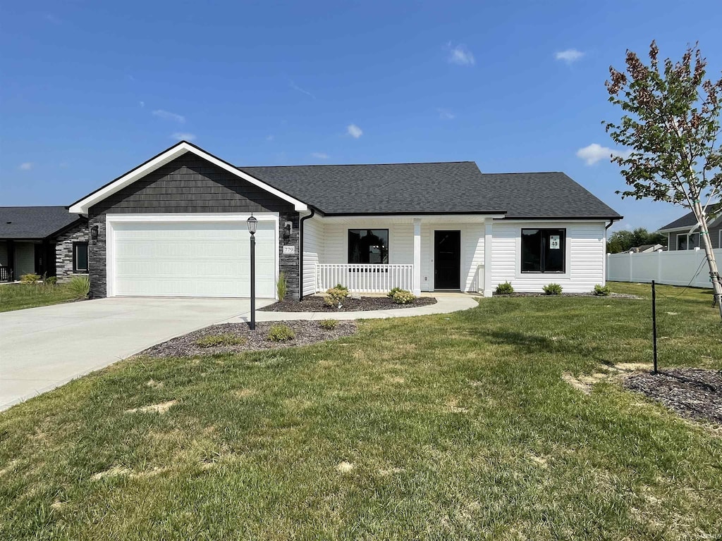 view of front of home featuring covered porch, a front yard, and a garage