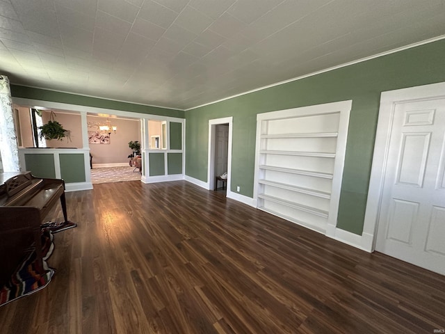 unfurnished living room with a notable chandelier, dark hardwood / wood-style floors, built in features, and ornamental molding