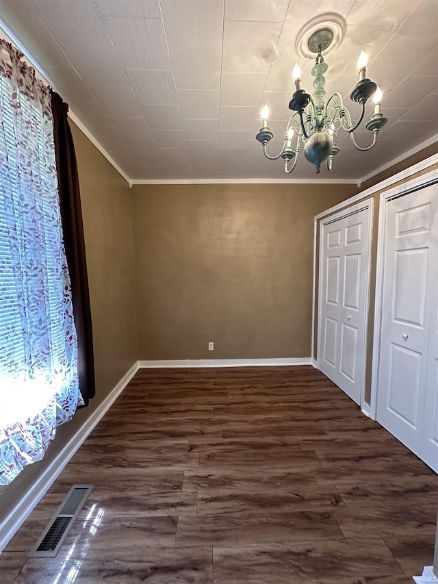 unfurnished dining area with dark hardwood / wood-style floors, an inviting chandelier, plenty of natural light, and crown molding