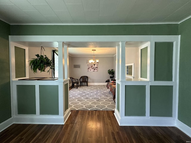 interior space with wood-type flooring, ornate columns, a notable chandelier, and crown molding