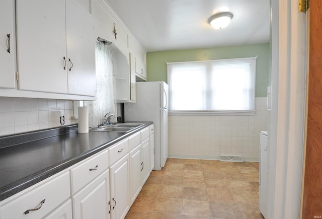 kitchen featuring white cabinetry, sink, tasteful backsplash, white fridge, and light tile floors