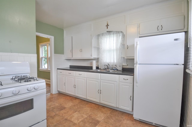 kitchen with white appliances, sink, white cabinetry, and light tile floors