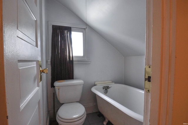 bathroom featuring a washtub, toilet, tile floors, and lofted ceiling